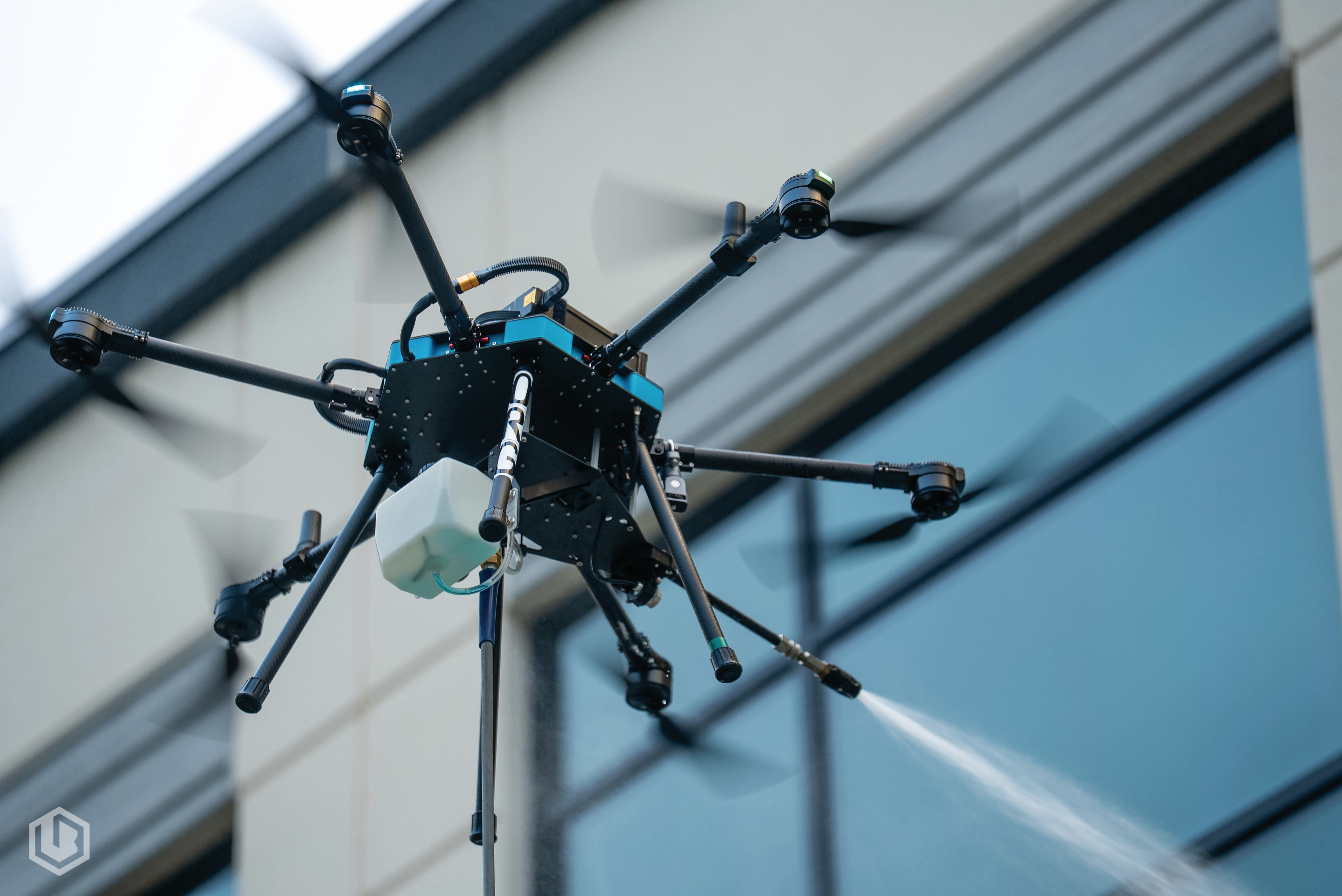 Lucid Bots Sherpa drone spraying and cleaning a commercial building facade